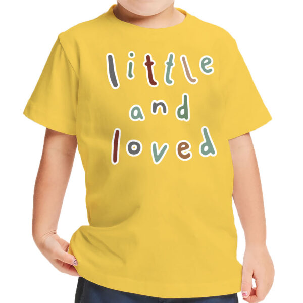 Toddler wearing a white t-shirt with "Little and Loved" print.