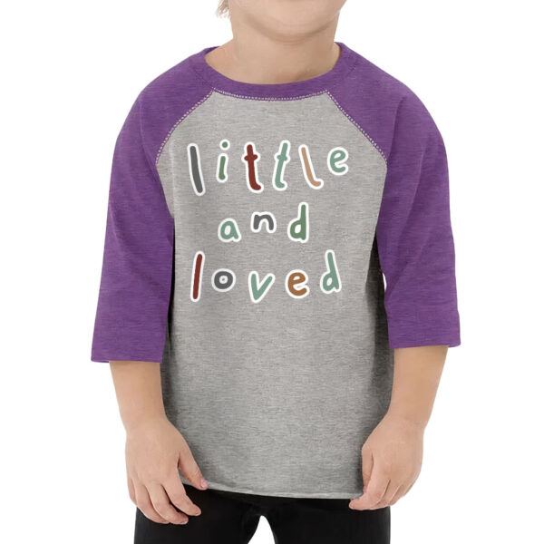 Toddler wearing a baseball-style t-shirt with "Little and Loved" print.